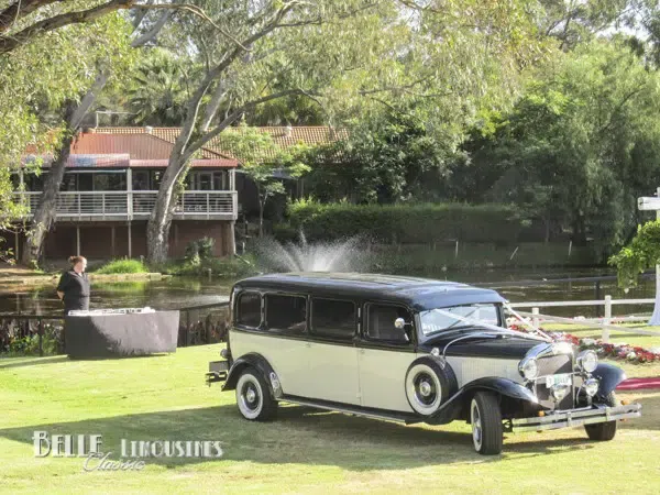A red carpet leading to a wedding venue with a limousine parked in the background