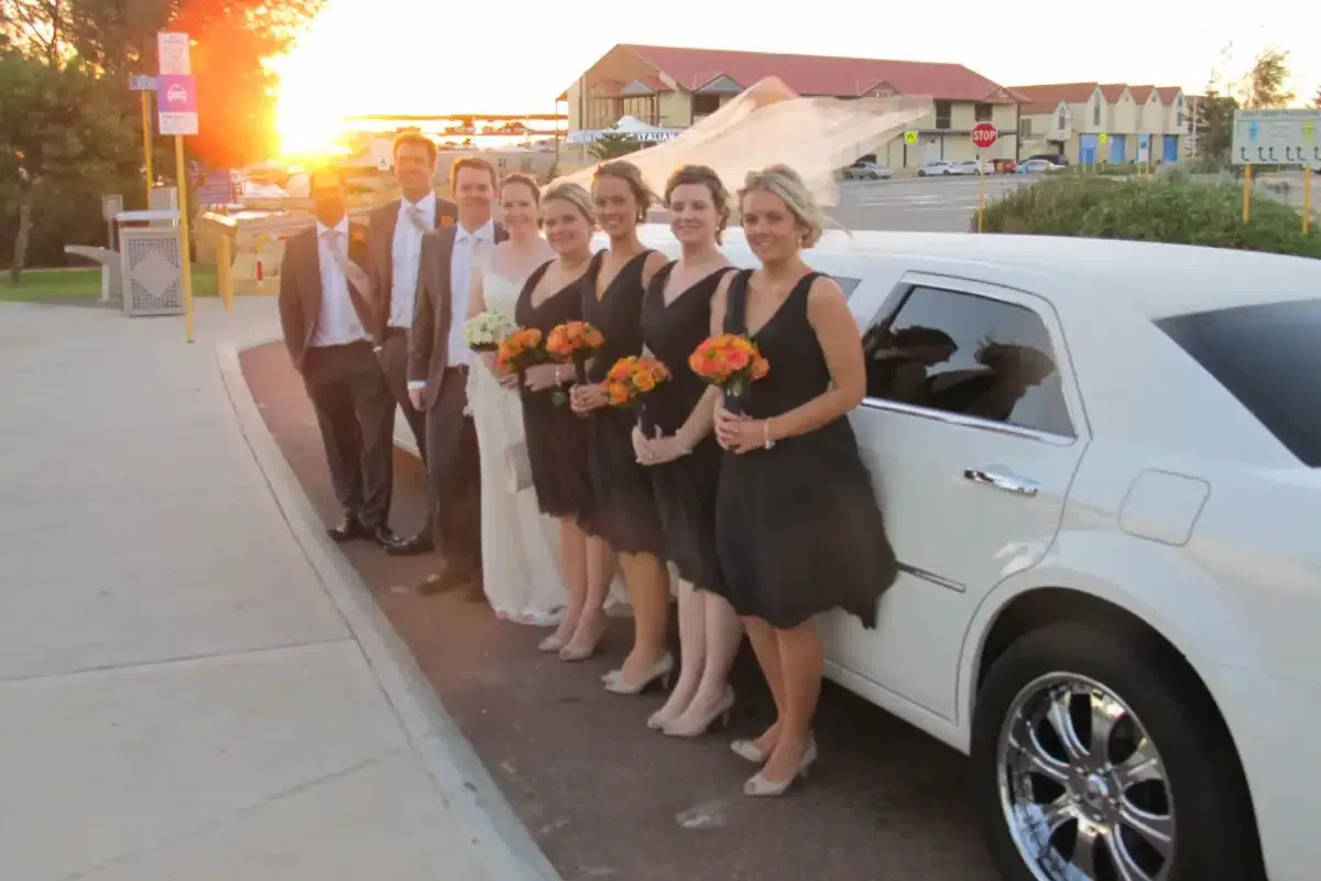 A white 10 seater stretch limousine with bridal party for a wedding