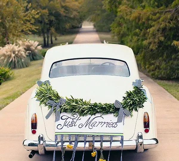 A wedding car with decorations on the license plate and bumper